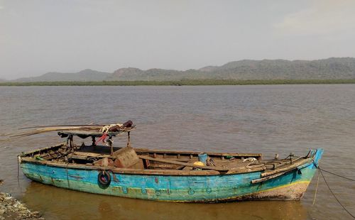 Fishing boats moored in lake against sky