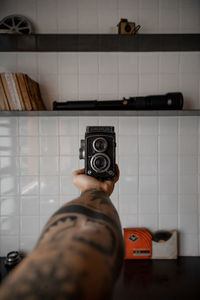 Man holding umbrella against wall at home