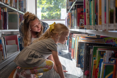 Mother with daughter choosing book in store