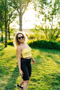 Full length portrait of woman wearing sunglasses on grass
