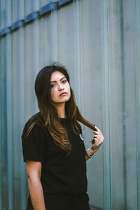 Portrait of beautiful young woman standing against wall