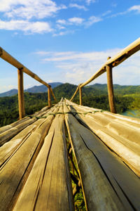 Surface level of wooden footbridge against sky