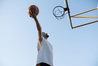 Low angle view of basketball player jumping with the ball
