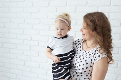 Mother and daughter standing in front of wall