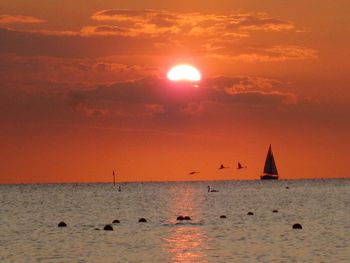 Silhouette sailboat sailing on sea against sky during sunset