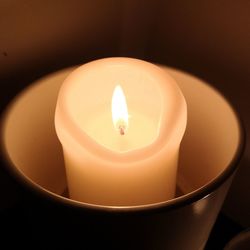 Close-up of lit tea light candle in darkroom