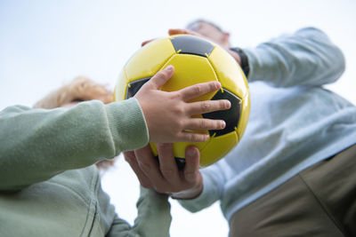 Midsection of man holding soccer ball