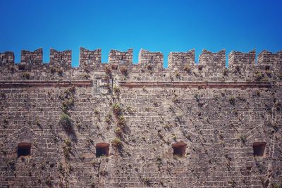 Low angle view of old building against clear blue sky