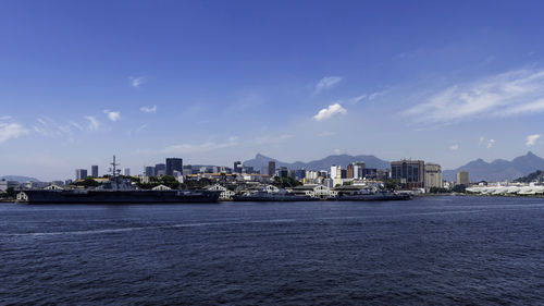 Sea by buildings against blue sky