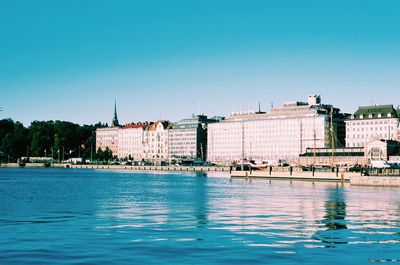 Sea by city against clear blue sky