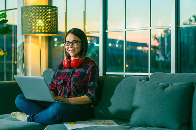 Portrait of smiling woman sitting on sofa at home