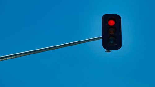 Low angle view of road signal against blue sky