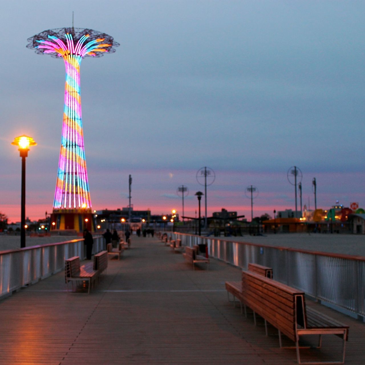 illuminated, built structure, sky, architecture, tourism, arts culture and entertainment, ferris wheel, building exterior, amusement park, travel destinations, city, famous place, street light, amusement park ride, incidental people, night, travel, dusk, tall - high, lighting equipment