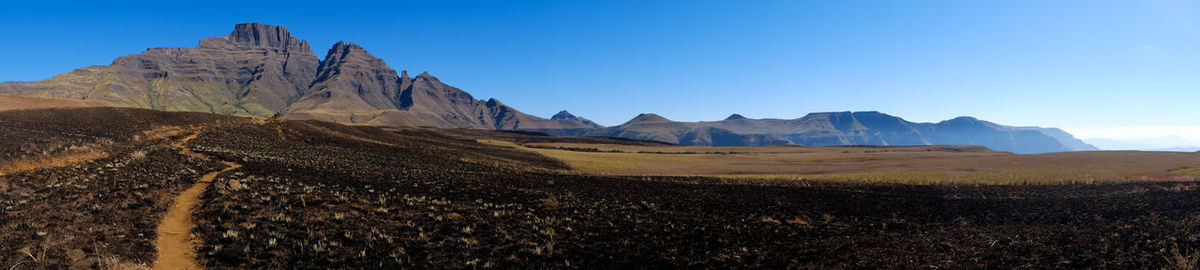 Panoramic view of rocky mountains against clear blue sky