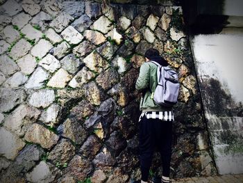 Rear view of man standing against wet stone wall