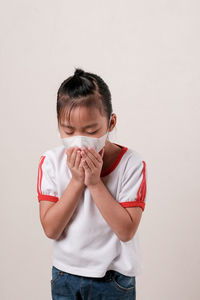 Portrait of a girl holding face against white background