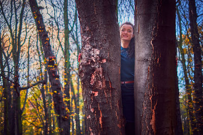 Portrait of smiling woman standing by trees in forest