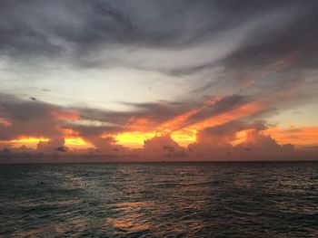 Scenic view of sea against dramatic sky during sunset