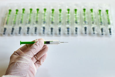 Cropped hand holding syringe against white background