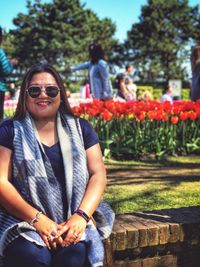 Portrait of smiling young woman with sunglasses against plants