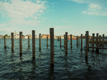 Wooden posts in sea against sky