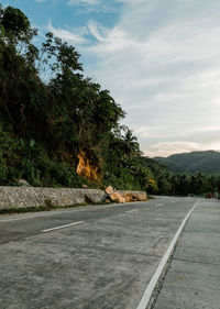 Road by trees against sky