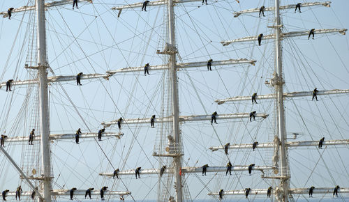 Men working on mast of cruise against sky