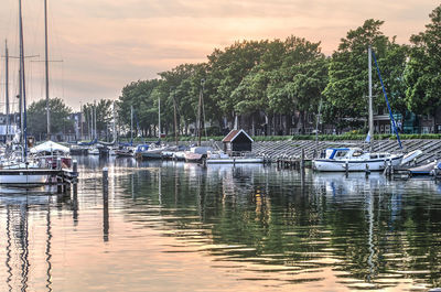 Boats moored in lake against sky during sunset