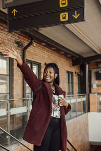 Portrait of happy young woman standing against text