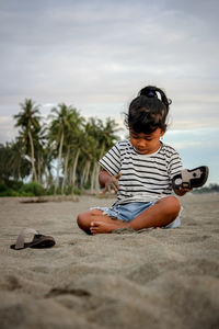 Women playing on sand at beach against sky