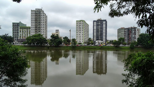 Lake by buildings against sky in city