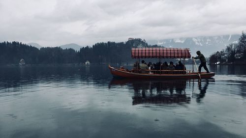 People on boat in lake against sky