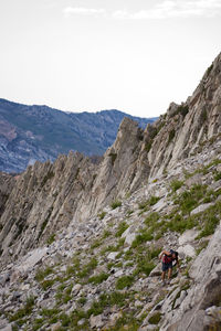 Hiker on rocky mountain against sky