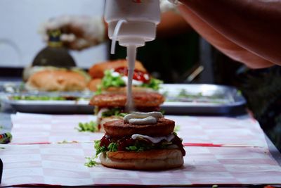 Close-up of hand holding burger on table