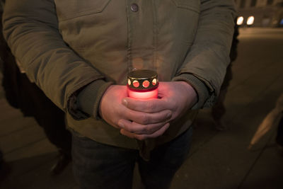 Midsection of man holding illuminated lighting equipment