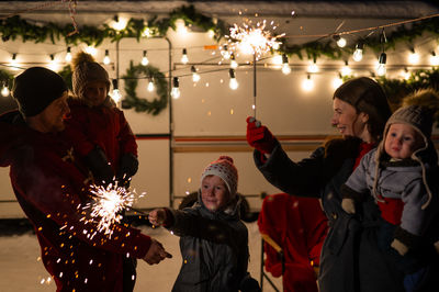 Happy family celebrates christmas in nature and holds sparklers. parents with three sons travels in