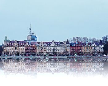 Reflection of building in river against sky in city