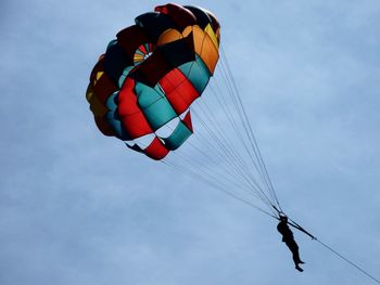 Low angle view of teenage boy parasailing against sky