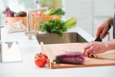 Cropped hands of man cutting eggplant on kitchen island