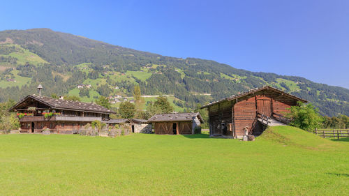 House on field by mountain against sky