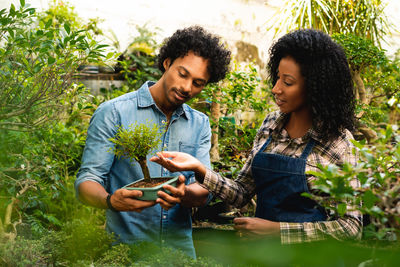 Side view of young woman holding plant