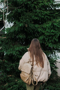Side view of woman looking away while standing against plants