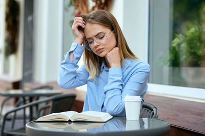 Young woman using mobile phone while sitting in cafe