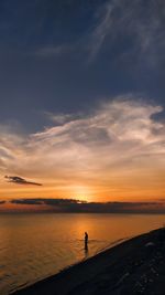 Silhouette people standing on beach against sky during sunset