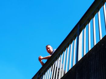 Low angle view of person on staircase against clear blue sky