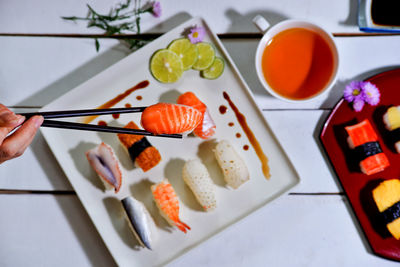 Cropped hand holding sushi with chopsticks