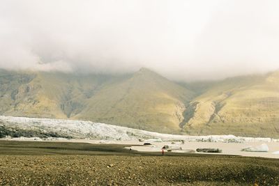 People on mountain by lake against sky