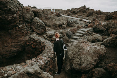 Rear view of woman standing at rock formation