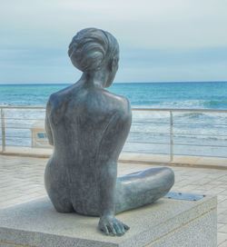 Statue on beach against sky
