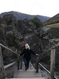 Full length portrait of young woman standing on rock